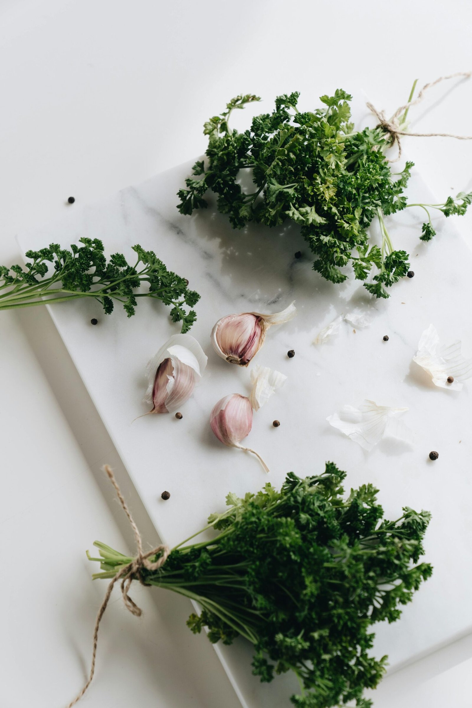 A rustic still life of fresh parsley and garlic cloves on a marble board, ideal for food themes.